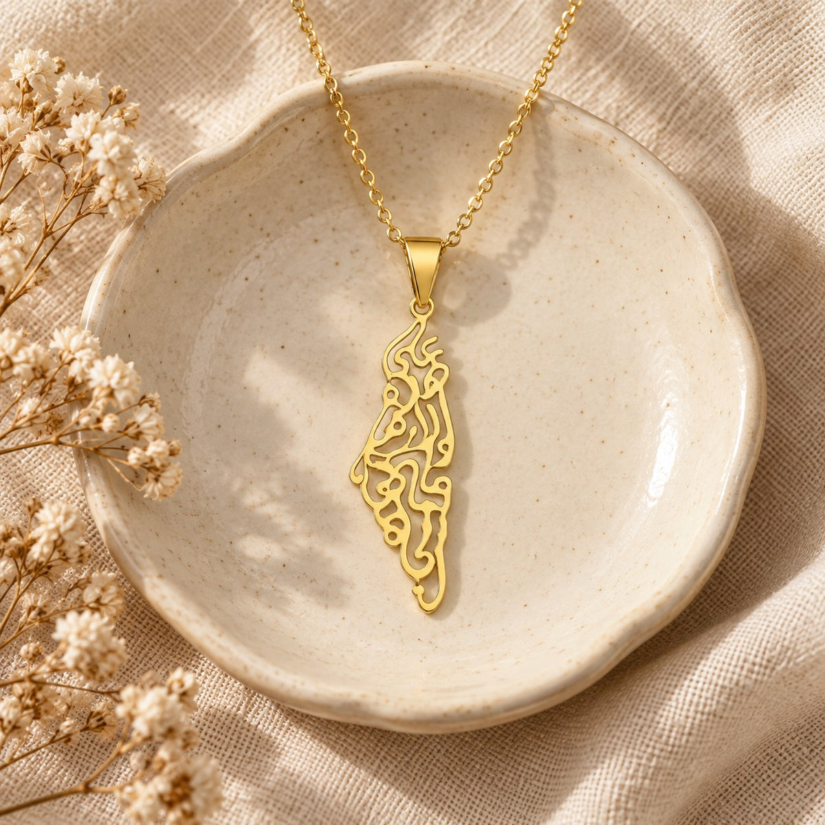 The Palestine Calligraphy Map Necklace in a ceramic trinket dish