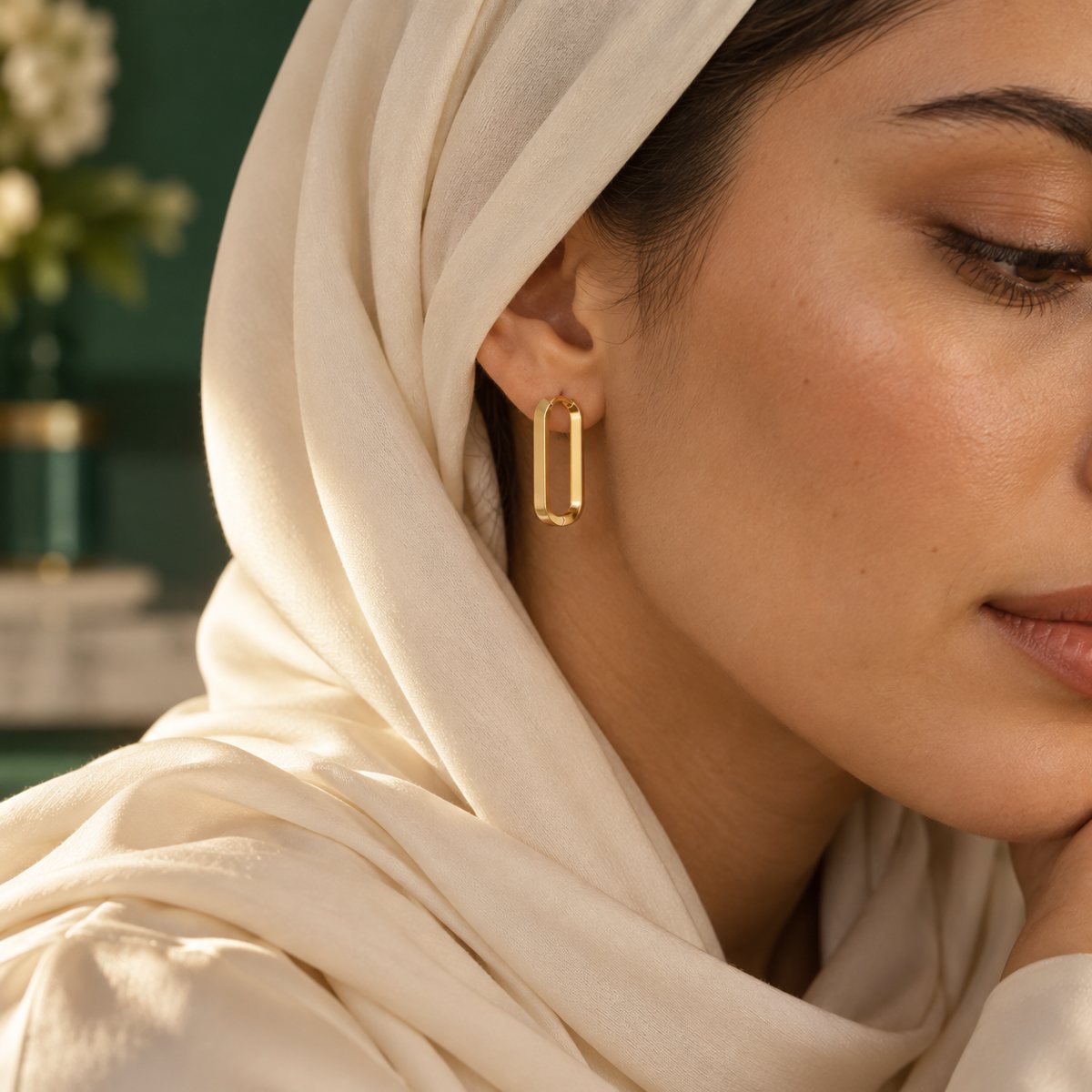 A woman wearing gold hoop earrings, hair tucked behind her ear