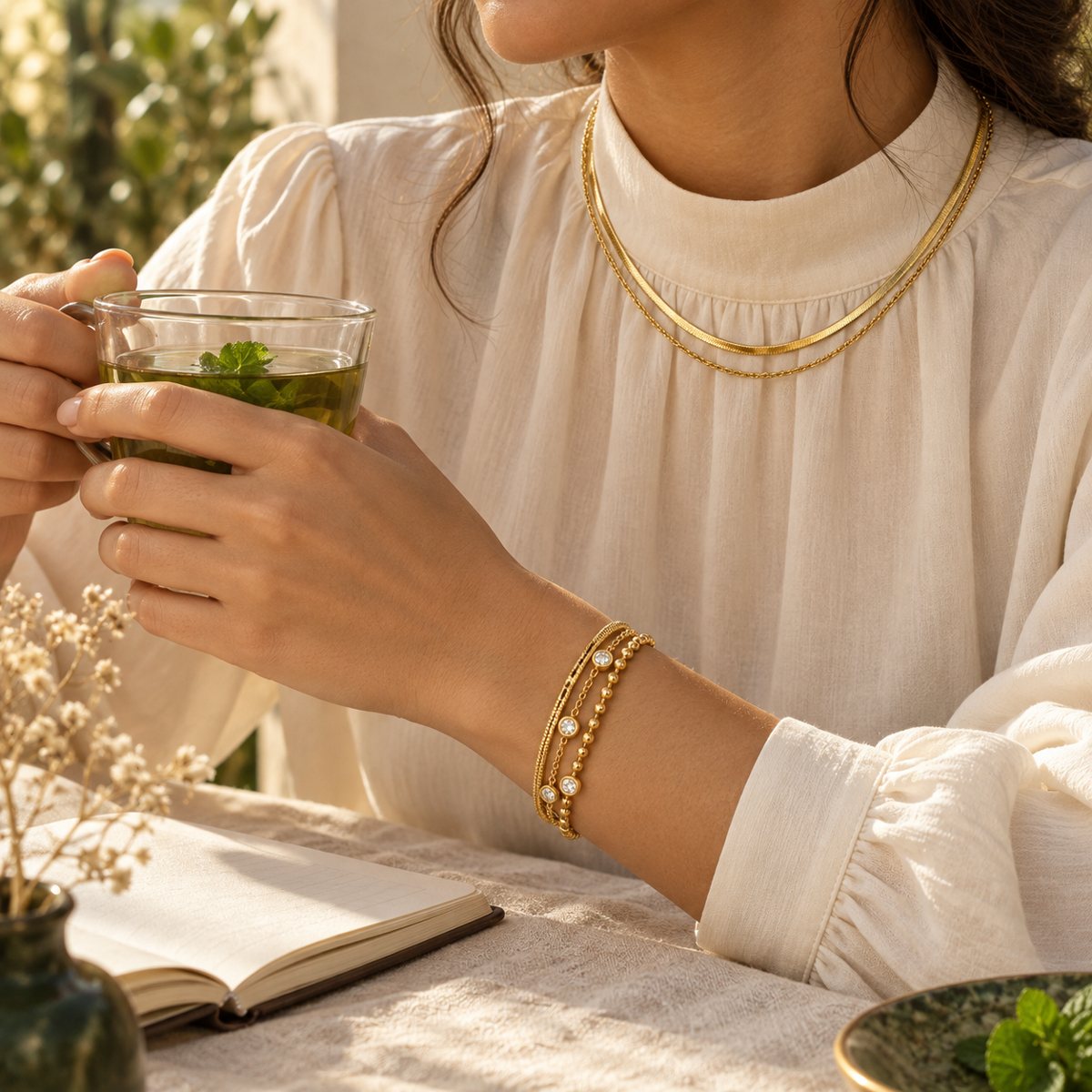 A woman wearing layered gold jewellery in soft morning light